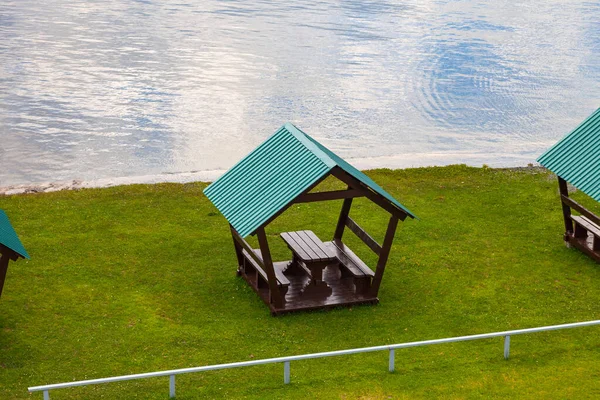 Nehrin kıyısında yeşil çatılı tahta bir çardak. — Stok fotoğraf