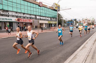 Erkekler ve erkekler maraton adı boyunca spor giyimli sporcular koşuyor.