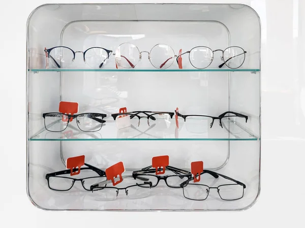 Shelving with glass shelves with glasses and frames in the optics store to improve vision and correct eyes. Ophthalmology and health.