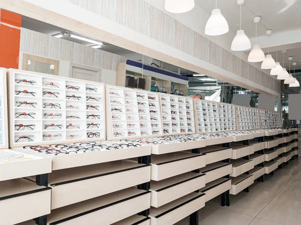 Shelving with glass shelves with glasses and frames in the optics store to improve vision and correct eyes. Ophthalmology and health.