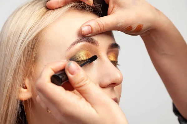 Makeup kunstner sætter på en orientalsk stil make-up med guld og gr - Stock-foto