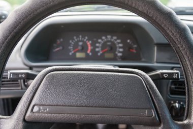 Beyaz sayılar, işaretler ve kırmızı seviyeli oklarla siyah bir zemin üzerinde hız, basınç ve sıcaklık ölçmek için sensörleri olan bir kontrol panelinin direksiyonu boyunca yakın çekim görüntüsü.