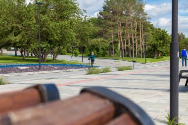 Novosibirsk, Rusya - 06.06.2020: Bir kız Novosibirsk 'teki Ob Nehri' nin setindeki bir parkta bisiklet yolu boyunca elektrikli scooter sürüyor. Yürümek, spor yapmak ve spor yapmak için modern bir araç.