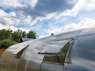 Dışarıdaki seranın otomatik pencereleri gökyüzüne karşı ve ağaçlar havalandırma için insan müdahalesi ve içerideki sıcaklık düzenlemesi olmaksızın..