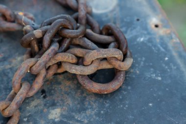 İskele demirli teknede dövülmüş eski metal zincir. Sudan mavi boya soyulmuş. Pas kaplı demir..