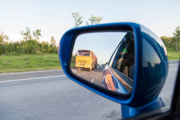 Widok Tyłu Lusterku Bocznym Niebieskiego Sedana Odbiciem Wyprzedzającej Żółtej Ciężarówki — Zdjęcie stockowe