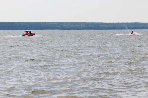 俄罗斯游客在河上度假的娱乐活动 乘坐汽艇和喷气式滑翔机高速滑行 背景是带着森林和天空的海岸 — 图库照片