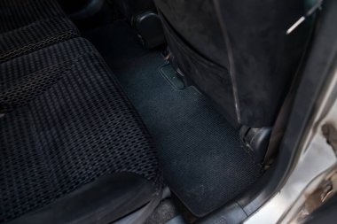 Bir oto hizmet merkezinde kuru temizlemeye verilmeden önce arka yolcu koltuğunun altında kirli koyu renkli araba paspasları var. Satış öncesi hazırlık.