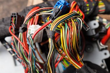 Arabanın elektrik kablolarında konnektörleri olan farklı renkte mat kablolardan oluşan bir kablo. Tedarikçinin çalışmasında internet hattı.