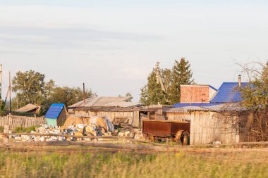 Arka bahçesinde ek binalar olan ve kışa odun hazırlamak için odun kesen eski tarz bir Rus köyünün kırsal manzarası..