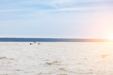 Bir motorlu tekne, yüksek hızda nehrin dalgaları boyunca yol alır. Bir yaz günü, gün doğumunda balıkçılık yaparken dalgaları suya düşürür..