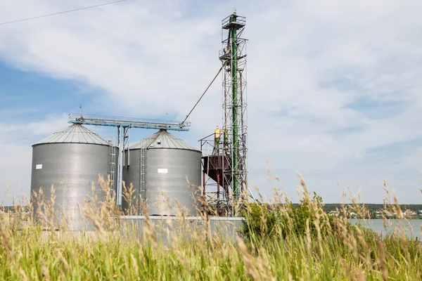 Mini station with metal tanks for storing crops or water supplies near the river in a sown field near the village.