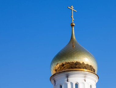 Beyaz kilisenin altın kubbesi ve Ortodoks haçı açık mavi gökyüzünün arka planında bir yaz günü. Hristiyanlar için bir güç ve inanç yeri ilan eden bir din..