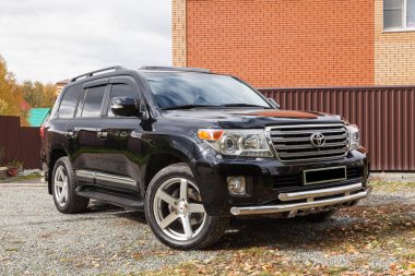 Novosibirsk, Rusya - 09.26.2020: Güneşli bir park gününde satıştan önce temizlik yaptıktan sonra siyah renkli Toyota Land Cruiser 200 öngörünümü. Japon SUV arabası.