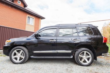 Novosibirsk, Rusya - 09.26.2020: Güneşli bir park gününde satıştan önce temizlik yaptıktan sonra siyah renkli Toyota Land Cruiser 200 'ün yan görüntüsü. Japon SUV arabası.
