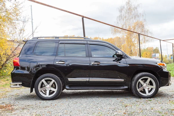 Novosibirsk, Rusya - 09.26.2020: Güneşli bir park gününde satıştan önce temizlik yaptıktan sonra siyah renkli Toyota Land Cruiser 200 'ün yan görüntüsü. Japon SUV arabası.