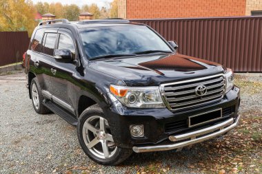 Novosibirsk, Rusya - 09.26.2020: Güneşli bir park gününde satıştan önce temizlik yaptıktan sonra siyah renkli Toyota Land Cruiser 200 öngörünümü. Japon SUV arabası.