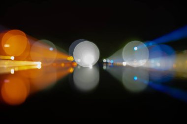 Soyut bokeh yeşil, sarı, kırmızı, siyah arka plan mavi sokak ışıkları. Gece hayatı ve su üzerinde yansıtmaktadır. Yakınlaştırma ve dijital hat kavramı.