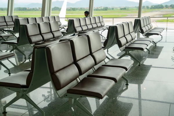 Chairs, benches, Seat Waiting lined for Departure passengers in airport and the taxi way and runway back ground. Empty lonely solitary concept.