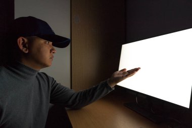 Adam Hacker yan görünüm oturup bilgisayar monitörü işaret parmakları monitör karanlık odada.