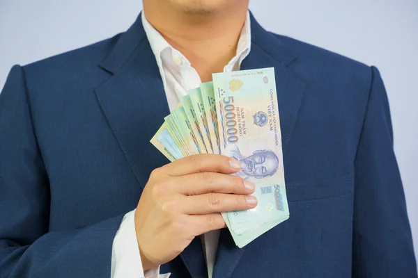 Geld in Vietnam hält Geschäftsmann im blauen Anzug in der Hand ( — Stockfoto