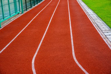 Açık hava spor stadyumunda beyaz çizgileri olan kırmızı koşu pisti Sid.