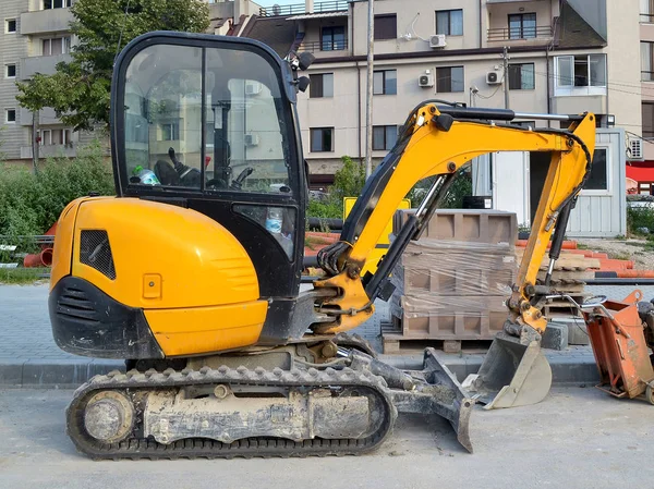 Sarı mini Ekskavatör caterpillar küçük inşaat işleri yerlere ulaşmak zor veya dar şehir sokakları, yan görünüm, yaz, gün için üzerinde