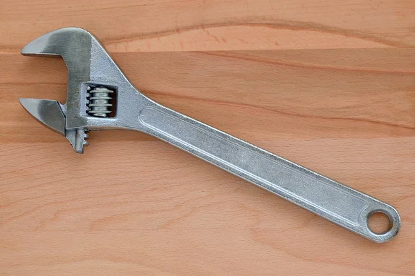 Metal adjustable wrench, tool for plumbers, on a brown natural wooden background, view from above