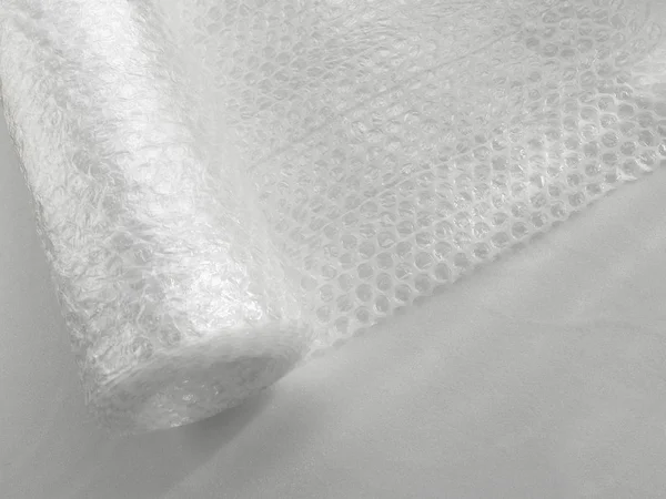 Transparent bubble wrap roll for packaging fragile items on white background, view from above