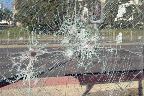 Close up of broken safety glass with many cracks at a bus stop on a city street on a day