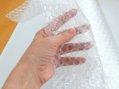 Kırılgan öğeleri paketleme şeffaf kabarcık şal el tutar, yakın çekim