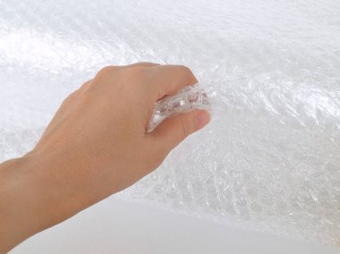 Kırılgan öğeleri paketleme şeffaf kabarcık şal el tutar, yakın çekim