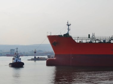 Küçük bir pilot gemi büyük kırmızı kargo gemisi liman rüzgarsız sıcak üzerinde bir sonbahar günü yol açar