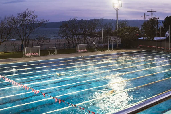 Varna, Bulgaristan, Kasım 2018. Yüzme karmaşık Primorsky Karadeniz kıyısında. Açık spor yüzme havuzu tarafından güçlü sahne ışıkları karanlık sonbahar akşam gökyüzü arka plan üzerinde yaktı.