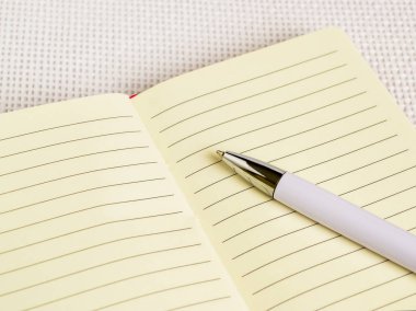 Üstünde pembe kapak beyaz arka plan kopya alanı üzerinde açılan defter beyaz tükenmez kalem