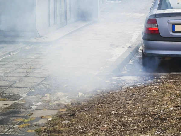Büyük bir konut binası, ekoloji, kentsel smog, hava kirliliği kavramı, dikey çerçeve avlusunda bir otomobilin egzoz borusu gri duman bulutu