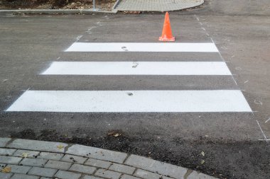 Bitmemiş yol bir yaya geçidi, sokağın karşısındaki çizgi. Islak beyaz boya yol işaretleme insan ayak izleri