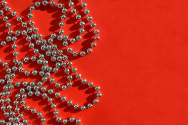 Parlak gümüş renkli boncuk Noel çelenk şenlikli düz yatıyordu, en iyi görünümü, kopya alanı parlak güneş ışığı altında dokulu kırmızı zemin üzerine.