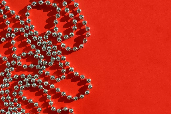 Parlak gümüş renkli boncuk Noel çelenk şenlikli düz yatıyordu, en iyi görünümü, kopya alanı parlak güneş ışığı altında dokulu kırmızı zemin üzerine.