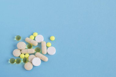 Bir yığın farklı hap ve kapsül mavi bir arka plan üzerinde. Hasta olmak için hap almak veya tedaviyi. Sağlık ve ilaç kavramı. Yat, yukarıdan görüntülemek, alan kopya.