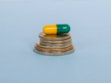 Bir ilaç kapsülü sikkeleri üzerinde mavi arka plan yakın çekim yığını var. Tıbbi ilaçların yüksek maliyet kavramı.