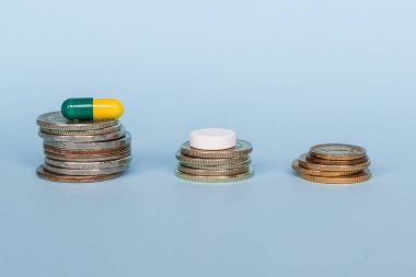 Bir ilaç kapsülü sikkeleri üzerinde mavi arka plan yakın çekim yığını var. Tıbbi ilaçların yüksek maliyet kavramı.
