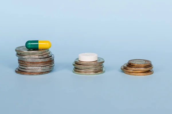 Uma Cápsula Medicamento Está Uma Pilha Moedas Fundo Azul Close — Fotografia de Stock