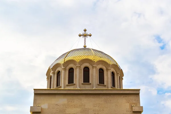 Golden dome with a cross on the Christian Orthodox Church. The gilded dome of the church against the blue sky with clouds. Christianity and orthodox christianity concept.