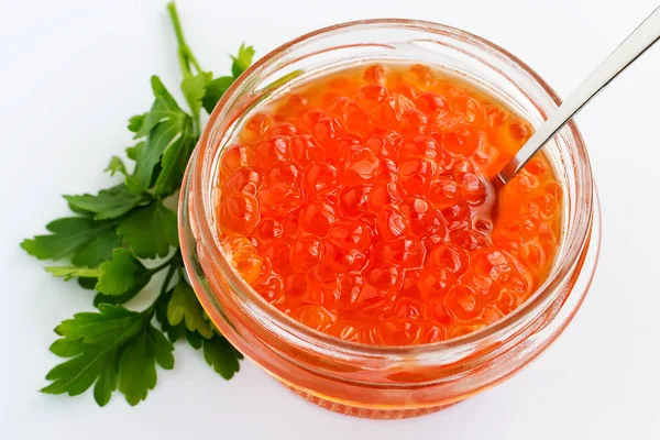 A glass jar of red caviar on a white background. Salmon caviar. Sea fish delicacy. View from above.