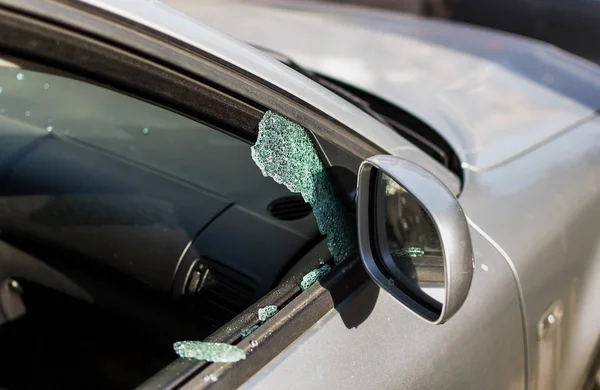 Car window smashed by a thief. Car broken window. Broken right side window of a car parked on the street. Theft from the car. A criminal incident. Hacking the car.