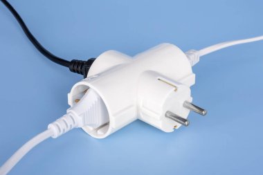Mavi bir arka plan üzerinde beyaz elektrik splitter içine ek ağaç fişler. Splitter aynı anda üç elektrikli ev aletleri geçiş yapmak için. Elektrik splitter ve fiş.
