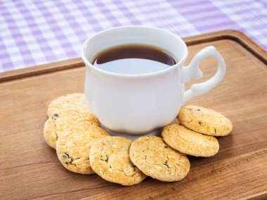 Beyaz porselen fincan çay ve tatlı yulaflı kurabiyeler.