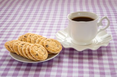 Dalgalı kenar ve yulaf ezmesi kurabiye ile tabak üzerinde çay ile porselen fincan