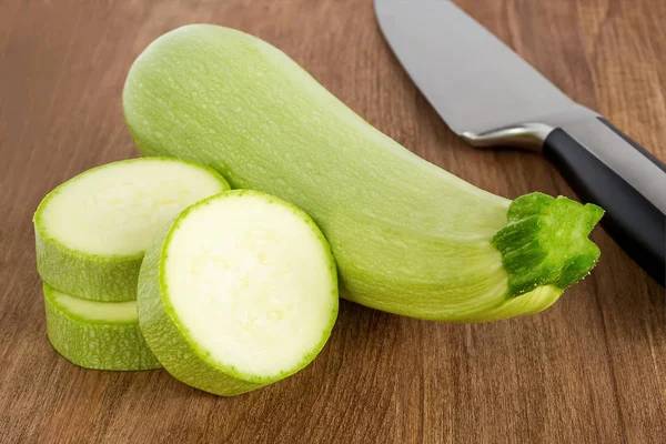 Courgettes vertes fraîches, quelques tranches et couteau de chef — Photo